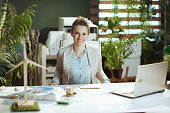 happy accountant woman in light business suit in green office
