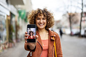 Cheerful mid adult woman showing her picture on her mobile phone