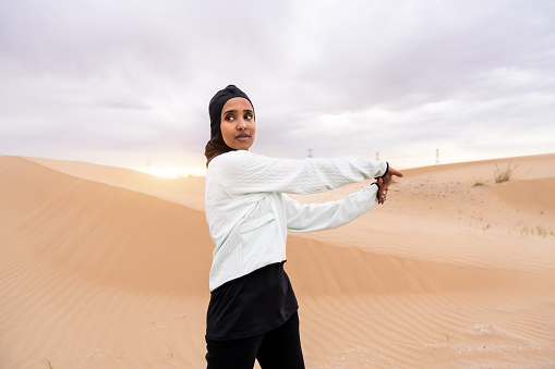 Beautiful middle-eastern arab woman wearing hijab training outdoors in a desert area - Sportive athletic muslim adult female wearing burkini sportswear doing fitness workout