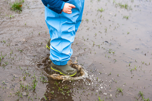 Cutout of a young child in park in a puddle during rainy weather