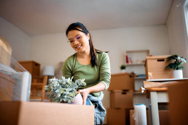 istock Happy Asian woman packing her plants while relocating into a new apartment. 1481853739