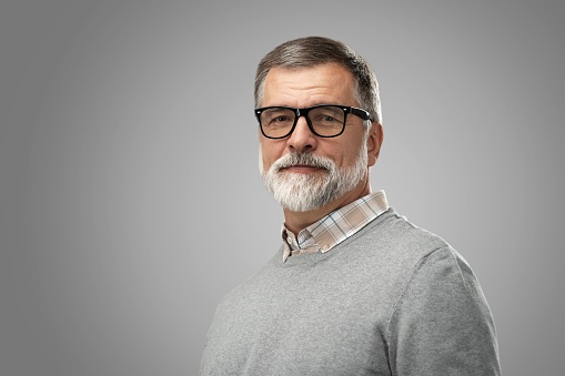 Portrait of handsome senior man in suit on gray background with copy space