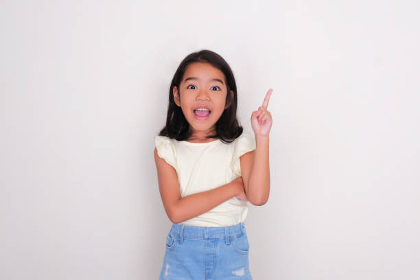 istock Asian little girl looking at camera and pointing finger up with excited expression 1481857821
