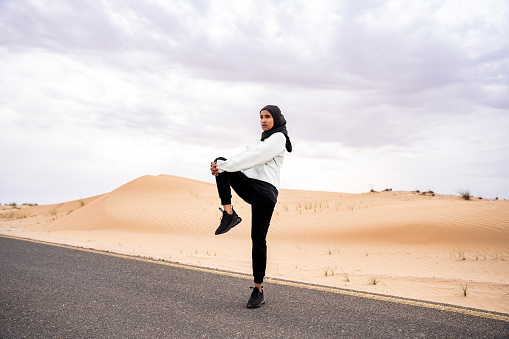 Beautiful middle-eastern arab woman wearing hijab training outdoors in a desert area - Sportive athletic muslim adult female wearing burkini sportswear doing fitness workout
