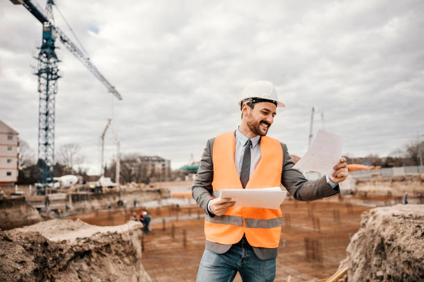 istock A happy engineer is standing on reconstruction area and looking at the blueprints. 1481860910