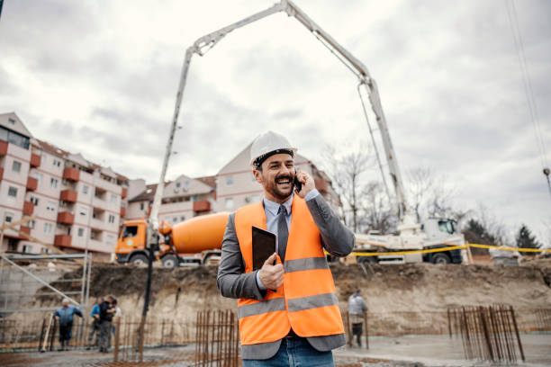 istock A happy site manager is holding tablet and talking on the phone while in a blurry background workers and machines working 1481861087