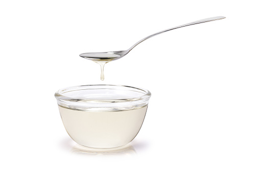 Sugar syrup in glass bowl and spoon isolated on white background.