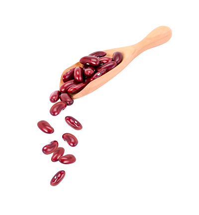 Red kidney bean falling from wooden scoop isolated on white background.