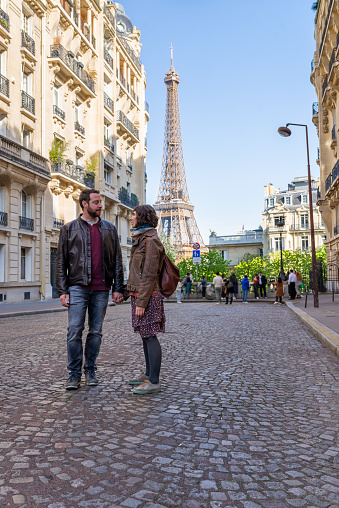 Man and woman holding hands and looking themselves during a romantic walk around Eiffel tower area in Paris.
