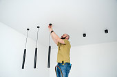 An adult man installing ceiling lights in the apartment
