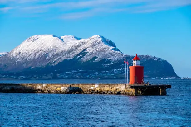 Snowcapped mountain range and Lighthouse in the city of Alesund, Norway.