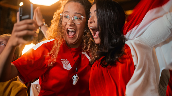 Portrait of an Excited Female Friends Holding Smartphone and Have Ecstatic Emotions When Football Team Scores a Goal. Win a High Stakes Casino Prize.