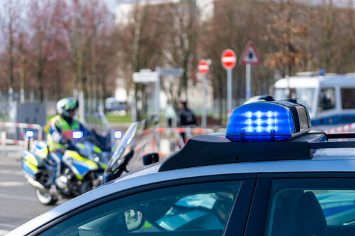 Blue Flash Light Of Police Car Against Police Officers On Motor Bike