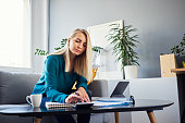 Young woman calculating home budget sitting on sofa at home