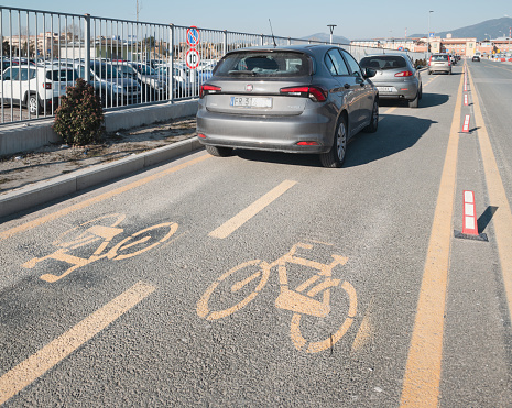 Pisa, Italy - February 13, 2023: the hospital in Cisanello is one of the largest in Europe, however plenty of its infrastructures are abandoned in decay. The image shows a long queue of cars that customarily parks in the bike lanes.