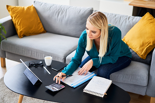 Picture of young woman doing accountancy work at home filling taxes