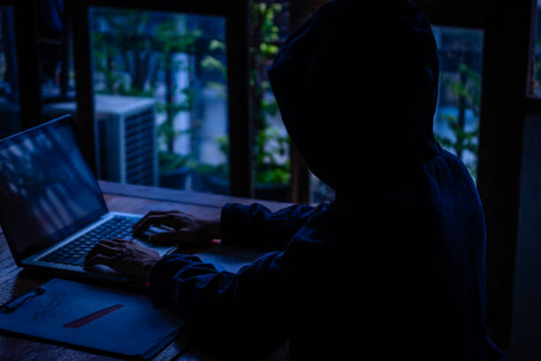 istock Hackers typing laptop computer keyboard In a dark room, wearing a hooded jacket over his head 1481877520