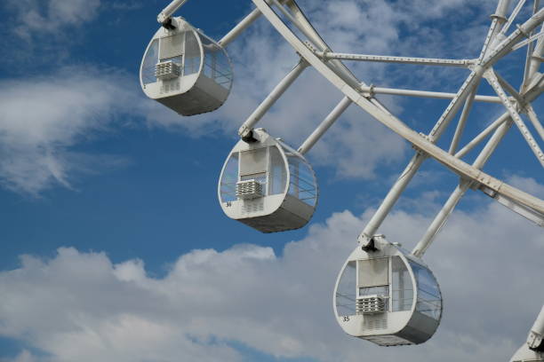 a white ferris wheel spins against a blue sky with blue clouds