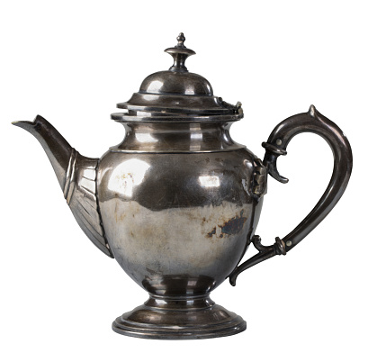 An antique metal teapot with an ornament on a white background. Old kettle with close-up lid.