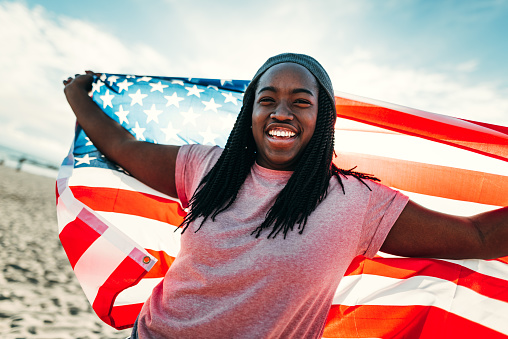 african woman with us national flag on the beach