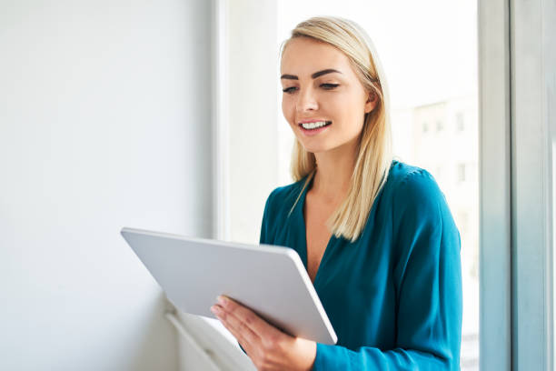 istock Smiling businesswoman using digital tablet standing next to  window 1481882078