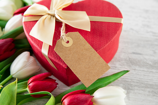 Mother’s Day and Valentine’s Day concept with red and white tulips and heart shaped gift box