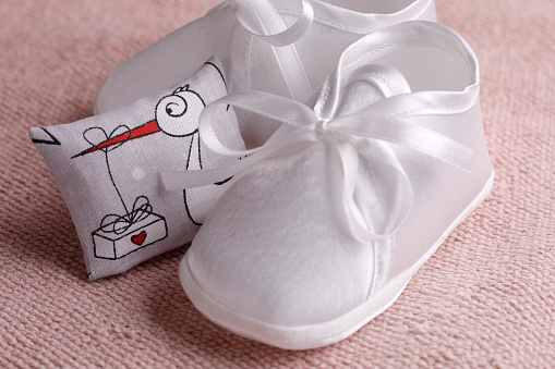 White baby booties and a stork on pillow