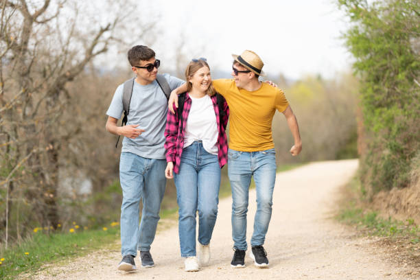 Joyful group of friends walking and embracing each other in nature. Teenagers enjoying outdoors.