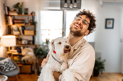 Portrait of a young man and cute schnauzer dog bonding at home