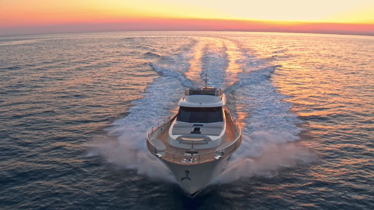 AERIAL Above a yacht travelling at sea in sunset