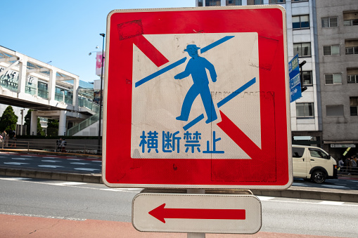 Tokyo, Japan - March 19, 2023: sign for people crossing street forbidden with arrow showing next pedestrian crossing.