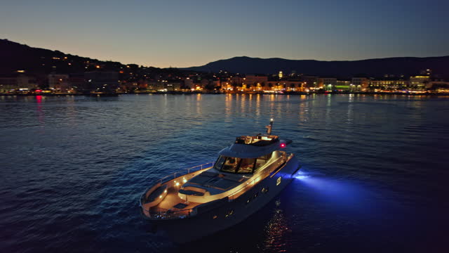 AERIAL Yacht moored in the bay of a coastal town at night