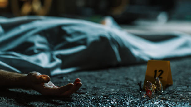 Cold Toned Picture: A Corpse Lying on the Floor and Covered. Victim's Hand is Peeking Out. Accidental Manslaughter Leaving Young Man for Dead. Glasses and Blood Marked as Evidence Next to the Corpse Cold Toned Picture: A Corpse Lying on the Floor and Covered. Victim's Hand is Peeking Out. Accidental Manslaughter Leaving Young Man for Dead. Glasses and Blood Marked as Evidence Next to the Corpse morgue stock pictures, royalty-free photos & images