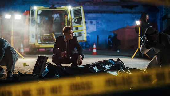 Do-not-Cross Tapes Restricting Access to Crime Scene in a Back Alley. Detective Inspecting the Body and Thinking About the Murderer's Motive. Smart Investigator Relating the Case to a Serial Killer