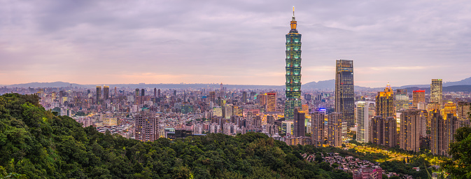 The glittering spire of Taipei 101 and the neon lights of downtown skyscrapers illuminated at sunset in the heart of Taiwan’s vibrant capital city.