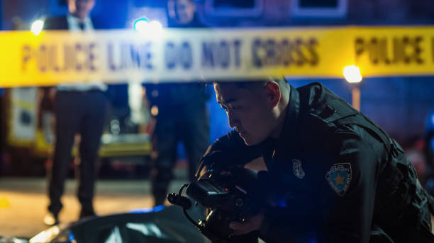 istock Police Department on Duty on a Crime Scene, Solving Murder Case. Young Asian Policeman Using a Camera to Take Forensic Photos of Evidence and Clues Found Around the Victim's Dead Body 1481902605