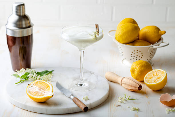 Elderflower gin sour with lemon and freshly picked elderberry flowers. Refreshing floral spring cocktail with elderflower cordial syrup stock photo