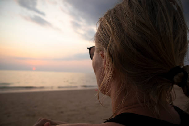 istock Melancholy woman sitting on the beach and staring the sunset 1481908454