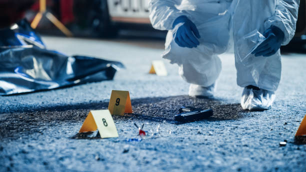 Forensics Finding Murder Weapon on Crime Scene at Night and Packing it in Professional Bag. Specialist Sending Gun to Lab to Look for Trace Evidence. Gang Fire Exchange Led to Mass Shooting los forenses encuentran un arma homicida en la escena del crimen por la noche y la empacan en una bolsa profesional. especialista enviando armas al laboratorio para buscar rastros de evidencia. intercambio de fuego de pandillas condujo a tiroteos masivos