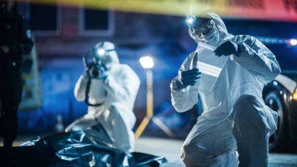 portrait of two forensics experts doing fieldwork at night at a crime scene. one technician taking photos of the dead body while the other packs the bloodied knife as murder weapon. - csi imagens e fotografias de stock