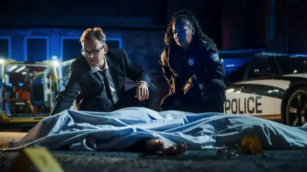 Team of Two Multiethnic Police Officers Working on Profiling a Killer on the Loose.Male Detective and a Policewoman Considering Clues and Evidence to Solve a Complicated Murder Case. Teamwork Concept
