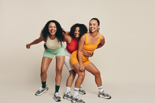 Group of young female athletes laughing and having fun in fitness clothing, celebrating their love for sport and exercise. Happy young sportswomen demonstrating their commitment to a healthy lifestyle.