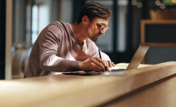 istock Focused graphic designer drawing on a graphics tablet in a cafe 1481917982