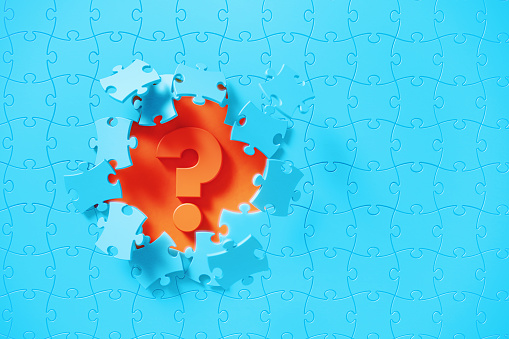 Blue jigsaw puzzle pieces revealing a question mark on orange background. Horizontal composition with copy space. Solution concept.