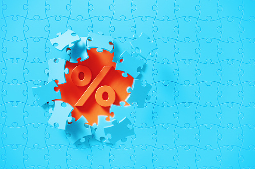 Blue jigsaw puzzle pieces revealing a percentage sign on orange background. Horizontal composition with copy space. Solution concept.