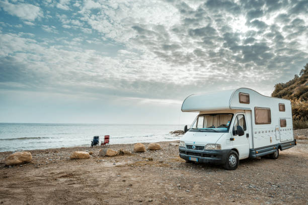 A camper and two chairs on the beach