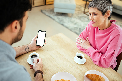 Couple is sitting at the table at breakfast time and using a mobile phone