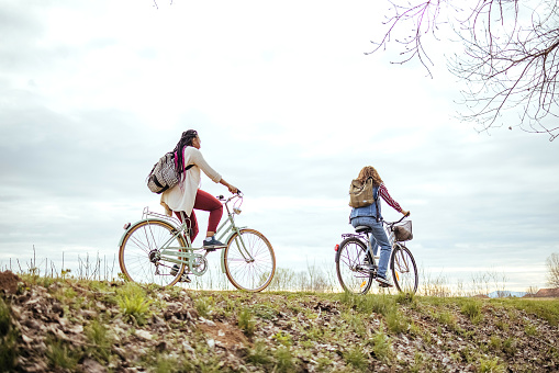 Two female friends ride a bike around the non-urban scene