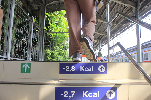 a woman is climbing the stairs of a train station in the city of Jakarta.