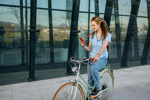 Woman sits on a bicycle and uses a mobile phone